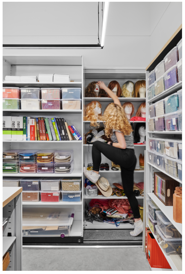 Woman reaching for a wig on a shelf as described on the imagine a place podcast with Manny Navarro