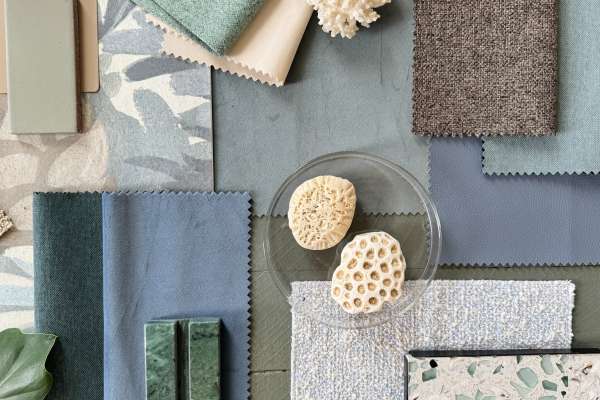 Flatlay arrangement featuring Haven velvet upholstery fabric with coordinating textiles, painted finishes, and organic accents in soft blues, greens, and taupe tones.