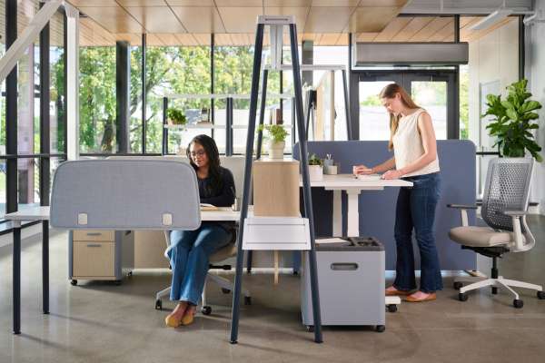 Kaleid flexible workstation with sit-stand desk, privacy panels, and mobile storage supporting individual and shared work