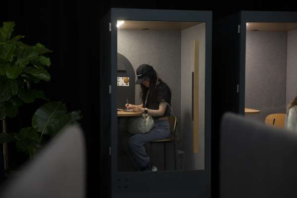 Woman in ROOM Phone Booth writing in notebook at ICFF 2026.