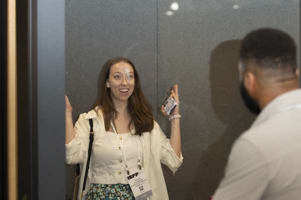 Woman excitedly smiling inside ROOM Phone Booth at ICFF 2026.