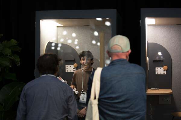 Man excitedly smiling inside ROOM Phone Booth at ICFF 2026.